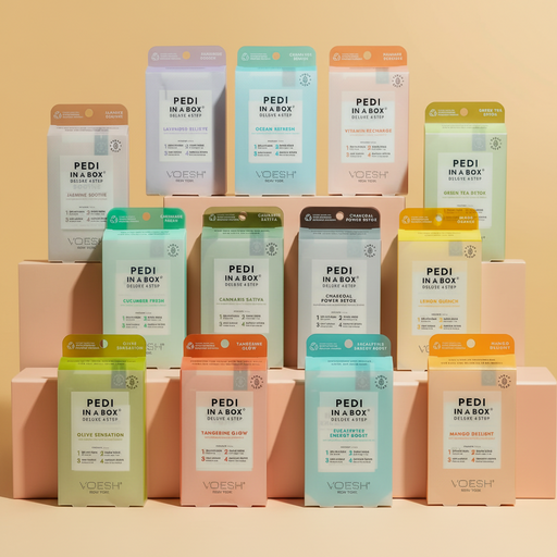 Various packages of 'Pedi in a Box' by Voesh on a beige background